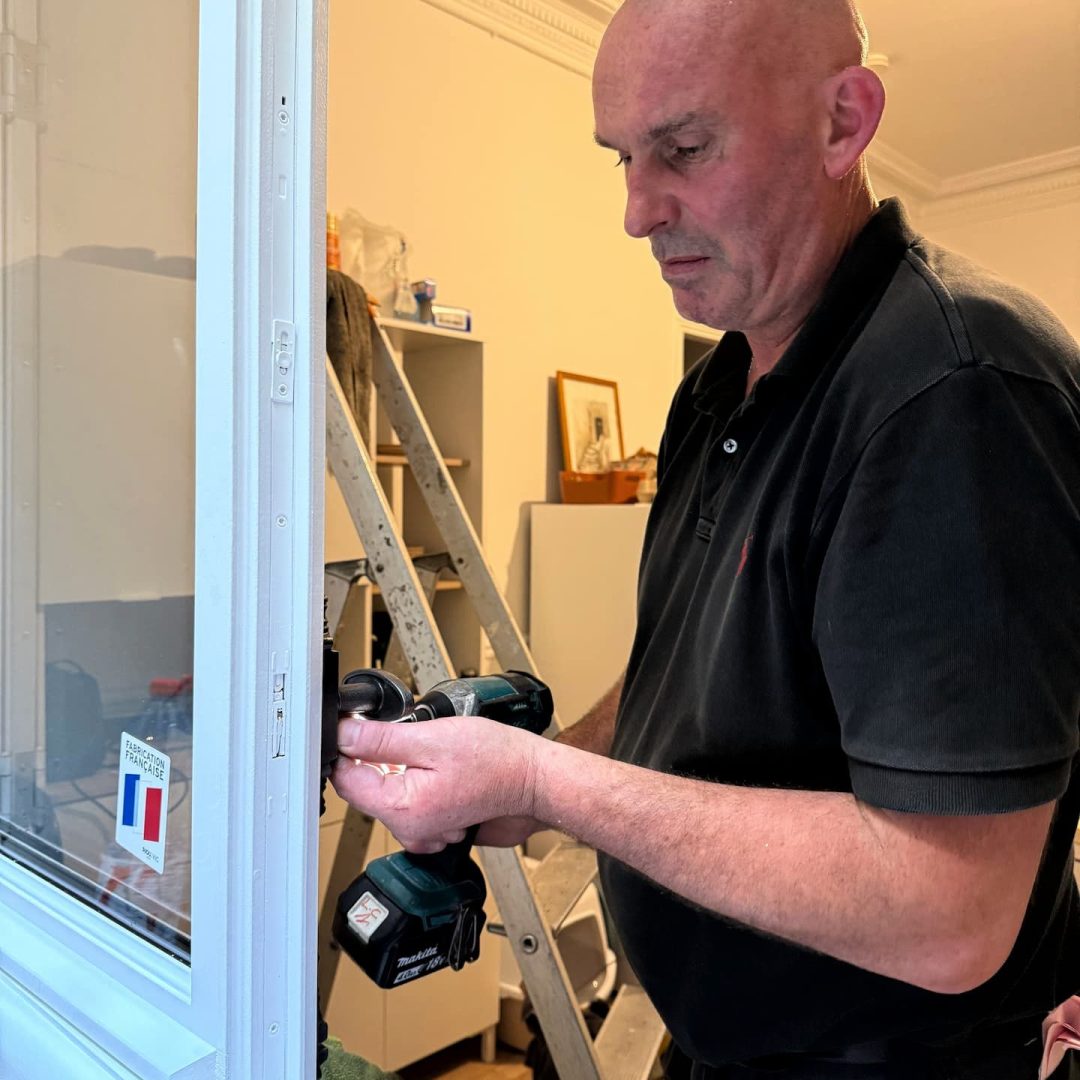 Ludovic COLAS, artisan menuisier en train de poser une fenêtre dans un appartement parisien.